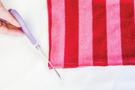 person trimming the corners off of red and pink fabric with scissors